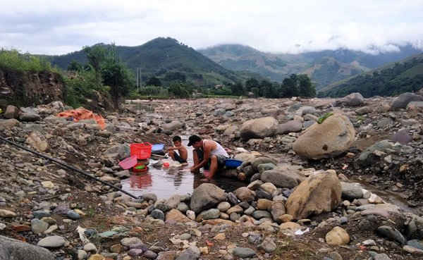 Hai bố con một gia đình đang dùng nước suối để sinh hoạt tại thị trấn Ít Ong