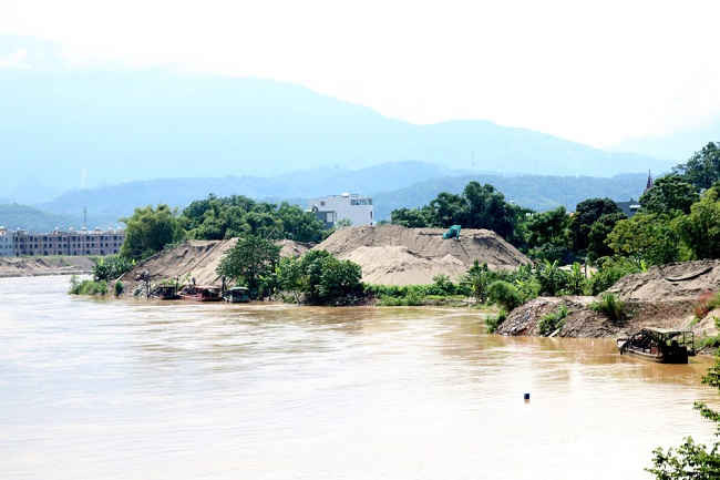 Dù đang bị đình chỉ hoạt động nhưng điểm tập kết của Công ty TNHH Phú Hùng (thành phố Lào Cai), cát vẫn chất cao như núi.