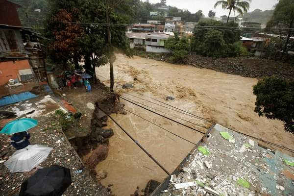 Mọi người nhìn con đường bị sụp đổ khi mưa lớn do bão Nate gây ngập sông Tiribi ở San Jose, Costa Rica vào ngày 5/10/2017. Ảnh: REUTERS / Juan Carlos Ulate