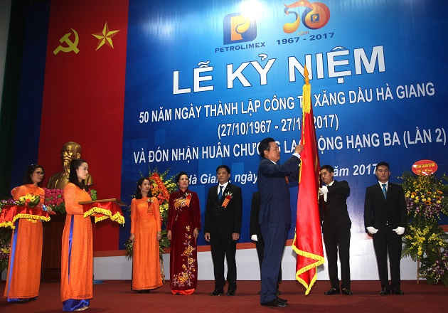 Chủ tịch UBND tỉnh Hà Giang Nguyễn Văn Sơn gắn Huân chương Lao động hạng Ba (lần 2) lên Cờ truyền thống của  Công ty Xăng dầu Hà Giang.