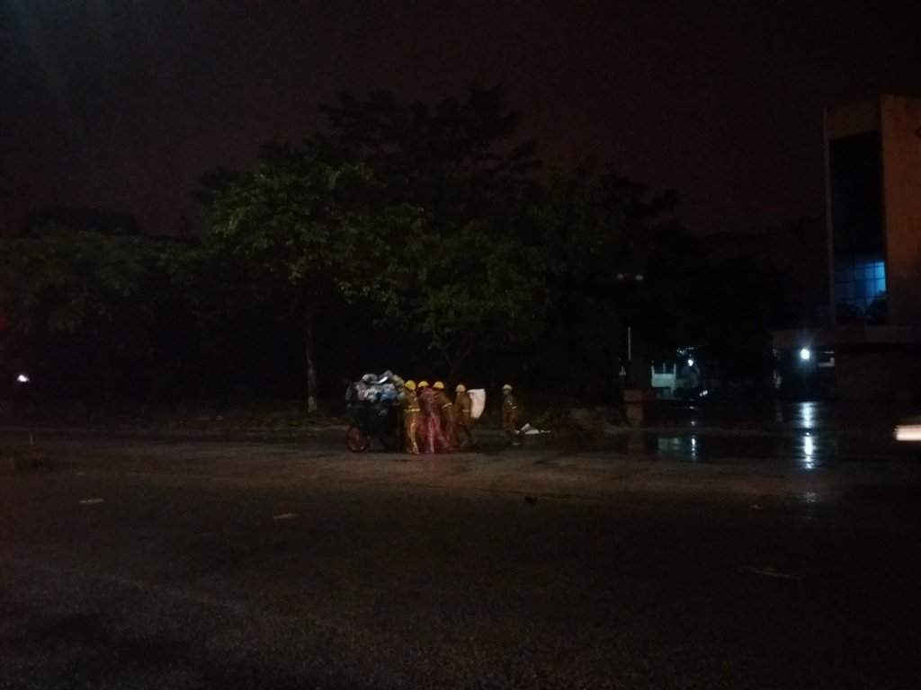 Những công nhân đẩy xe rác trong đêm mưa