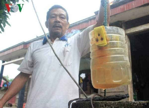 Ông Nguyễn Mạnh Hà, thôn 1, Phong Nha kéo chiếc gàu múc nước bị đóng váng vì nước phèn.