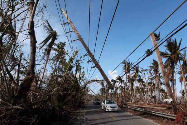 Các xe ô tô chạy dưới một cột điện bị đổ sập sau khi bão Maria đổ bộ Naguabo, Puerto Rico hồi tháng 9/2017. Ảnh: Reuters / Alvin Baez