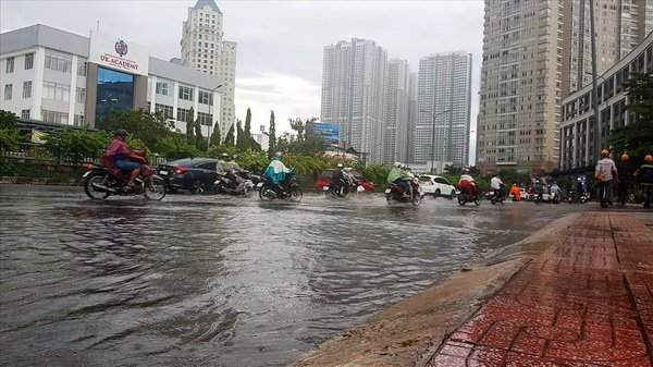 Nước tràn từ cống chạy dọc chân cầu Thủ Thiêm rồi hòa vào đường Nguyễn Hữu Cảnh chiều nay. Ảnh: Trường Sơn