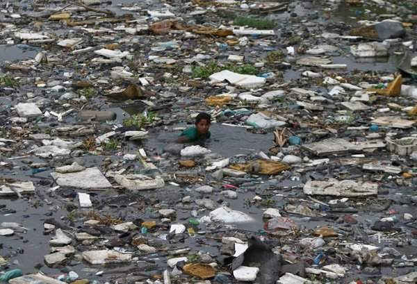 Một cậu bé đang mò cá trong dòng nước ô nhiễm gần bãi biển ở thành phố Chennai, miền Nam Ấn Độ vào ngày 3/7/2013. Ảnh: Reuters/ Babu