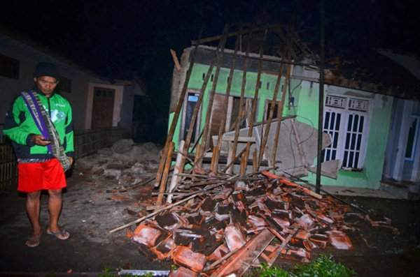 Người dân làng Sumelap đứng gần ngôi nhà bị phá hủy sau trận động đất xảy ra tại ngôi làng này ở Tasikmalaya, Indonesia vào ngày 16/12/2017. Ảnh: Antara Foto