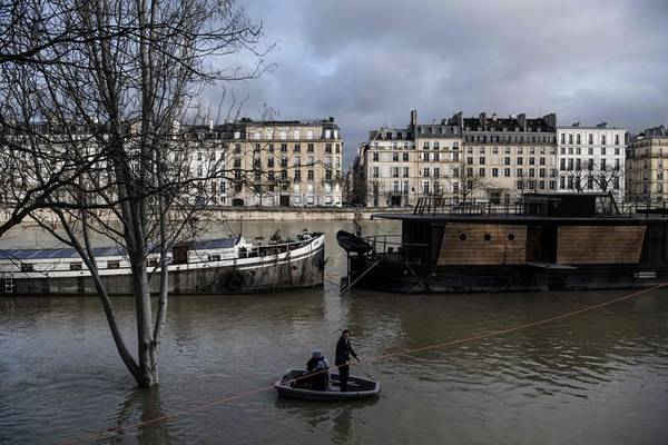 Mọi người sử dụng một chiếc thuyền nhỏ để rời khỏi chiếc sà lan neo đậu trên sông Seine. Hình ảnh: Christophe Archambault / AFP / Getty Images