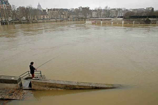 Một người đàn ông câu cá trên bờ sông Seine ngập nước. Hình ảnh: Pascal Rossignol / Reuters