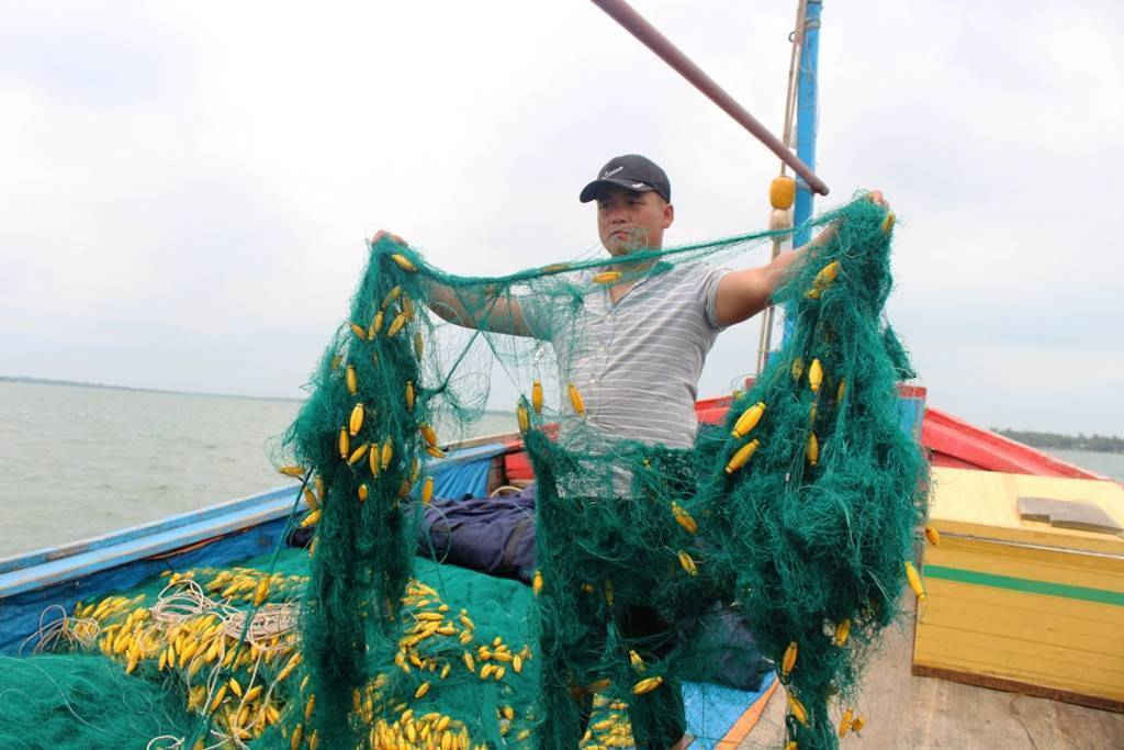 Ngư dân Nguyễn Tấn Sơn cầm tấm lưới bị các người trên tàu lạ cắt hư hỏng