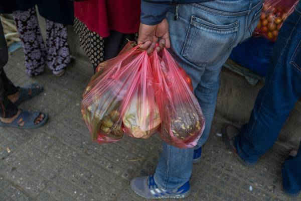 Một người đàn ông đựng rau củ quả trong nhiều túi polythene tại Chợ rau củ quả Kalimati. Rất ít người sử dụng túi không phải là túi nilon để mua hàng. Ảnh: Nabin Baral