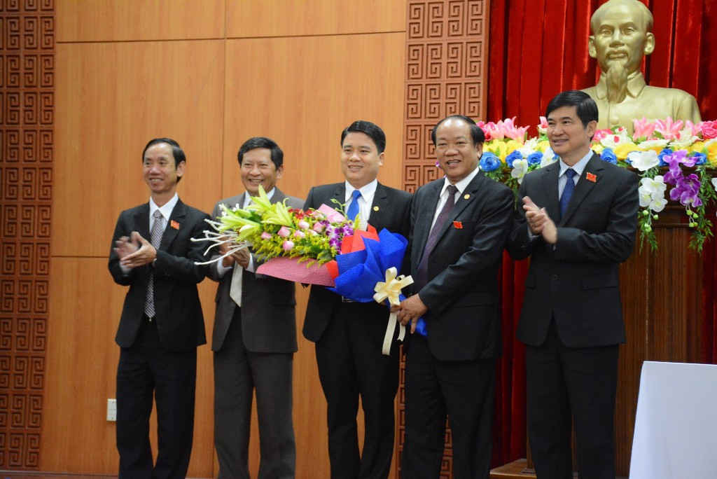 Ông Trần Văn Tân (giữa) nhận hoa chúc mừng từ ông Đinh Văn Thu, Chủ tịch UBND tỉnh Quảng Nam