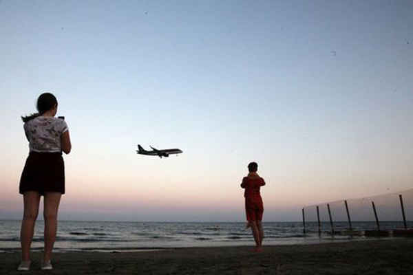 Du khách chụp ảnh trên bãi biển trong khi máy bay chuẩn bị hạ cánh tại Cộng hòa Síp vào ngày 22/10/2017. Ảnh: Yiannis Kourtoglou