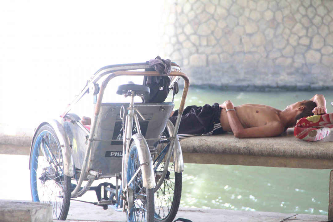 Một bác chạy xích lô ngủ trưa dưới cầu Trường Tiền