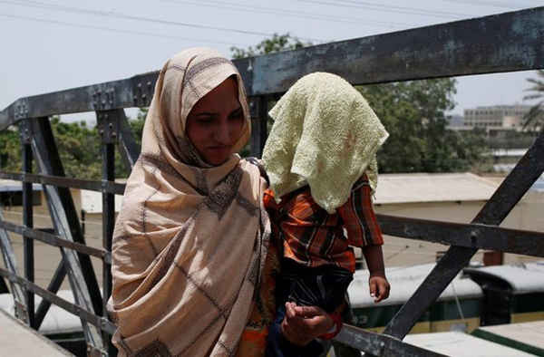 Một người mẹ bế con và dùng khăn để che nắng cho con trong đợt nắng nóng ở Karachi, Pakistan vào ngày 21/5/2018. Ảnh: Akhtar Soomro