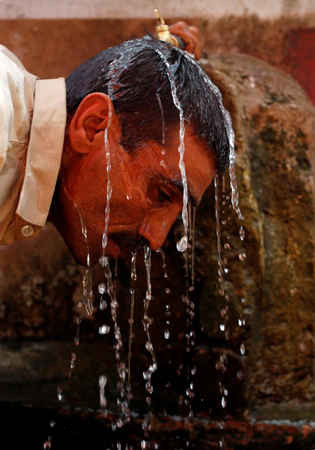 Một người đàn ông để vòi nước công cộng chảy vào đầu và mặt để dịu đi cơn nóng ở Karachi, Pakistan vào ngày 21/5/2018. Ảnh: Akhtar Soomro