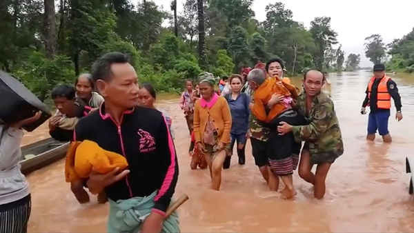 Người dân lội qua vùng nước lũ sau khi được giải cứu an toàn bằng thuyền ở huyện Sanam Xay, tỉnh Attapeu, Lào