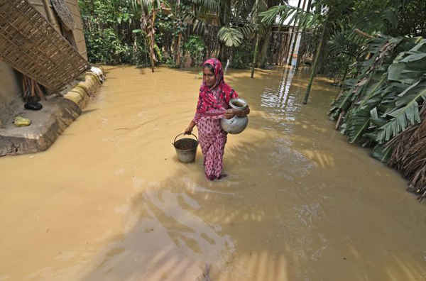 Người phụ nữ mang nước uống sau khi lấy nước từ một bơm quay tay tại khu vực bị ảnh hưởng lũ lụt ở quận Hojai, bang Assam, Ấn Độ vào ngày 17/6/2018. Ảnh: Anuwar Hazarika