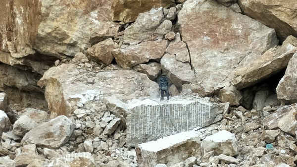 Thợ đang khoan đá tại núi, bên cạnh là những tảng đá to bị rạn nứt có nguy cơ đổ sập