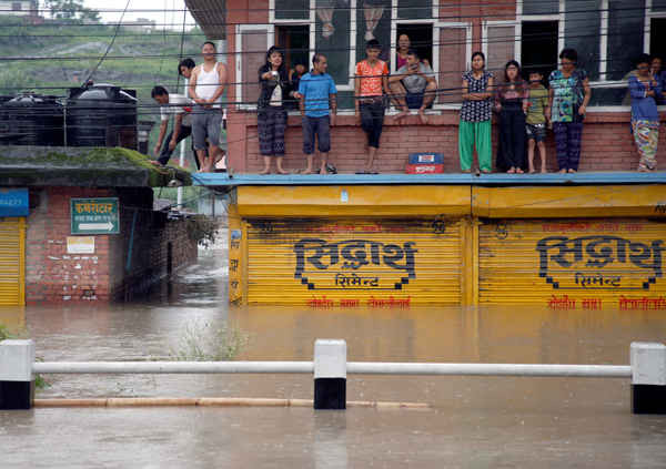 Người dân đứng trên ban công của một ngôi nhà nằm trong khu vực bị ngập lụt sau trận mưa không ngừng ở Bhaktapur, Nepal vào ngày 12/7/2018. Ảnh: Navesh Chitrakar