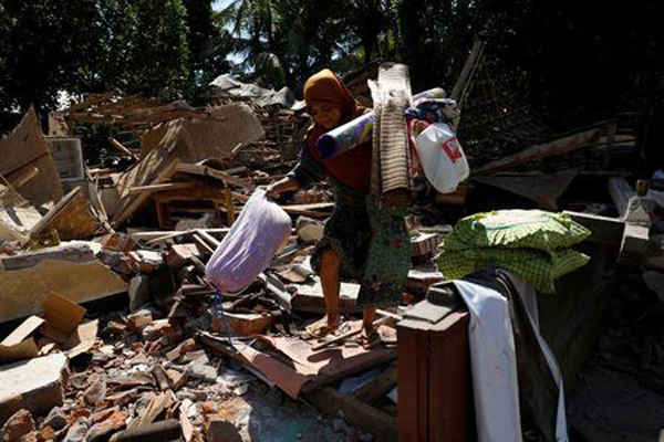Một người phụ nữ chuyển những đồ dùng thiết yếu từ đống đổ nát của ngôi nhà của mình tại huyện Kayangan sau khi trận động đất xảy ra vào tối 5/8 ở Bắc Lombok, Indonesia, ngày 7/8/2018. Ảnh: Beawiharta