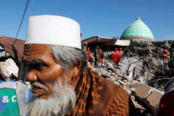Người dân làng đứng thất thần trong khi đội cứu hộ đang cố gắng để tìm kiếm những người đang mắc kẹt trong nhà thờ Hồi giáo sau trận động đất tấn công Pemenang ở đảo Lombok, Indonesia. Ảnh: Beawiharta