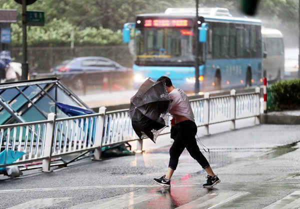 Người đi đường che ô trong khi gió lớn do bão Yagi gây ra ở thành phố Hàng Châu, tỉnh Chiết Giang, Trung Quốc vào ngày 13/8/2018