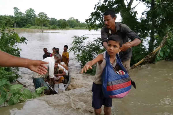 Một cậu bé cố gắng để bảo vệ sách giáo khoa của mình khi sông Dhansiri ngập nước do lũ ở bang Assam, Ấn Độ. Ảnh: Rubul Ahmed