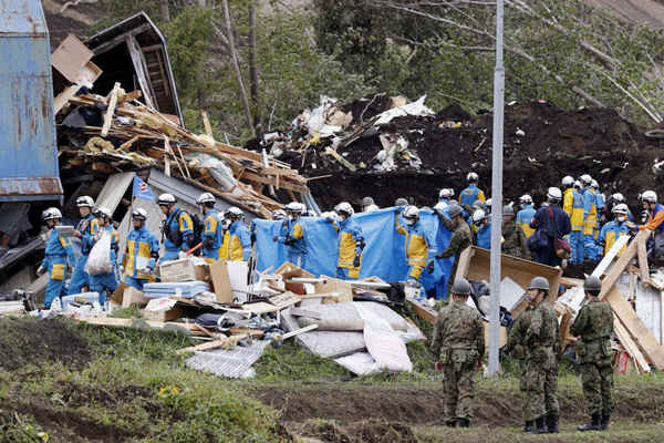 Cảnh sát và các thành viên của Lực lượng Phòng vệ Nhật Bản (JSDF) cứu một người mất tích được tìm thấy từ khu vực bị phá hủy trong trận động đất tại thị trấn Atsuma, Hokkaido, miền Bắc Nhật Bản vào ngày 8/9/2018