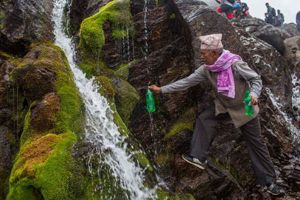 Một người hành hương hứng nước thánh từ nguồn nước chính của hồ Gosaikunda. Ảnh: Nabin Baral