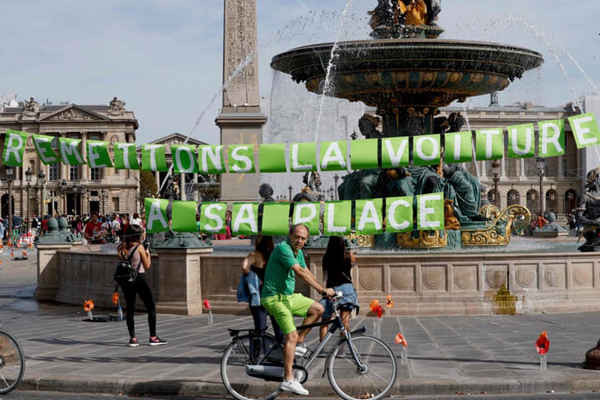 Tận hưởng một ngày không có xe hơi ở Paris (Pháp), một người đàn ông đạp xe trước đài phun nước có dòng chữ “Hãy để xe hơi trở lại chỗ của nó”. Ảnh: Francois Guillot / AFP / Getty Images