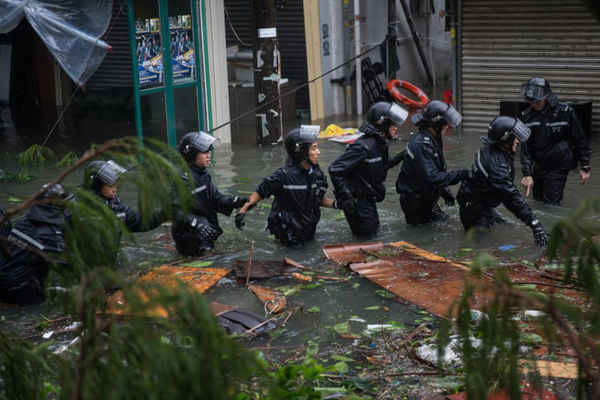 Nhân viên cảnh sát đứng thành hàng dài trên con đường bị ngập lụt trong một cuộc giải cứu tại Lei Yue Mun, Hồng Kông, Trung Quốc. Ảnh: Jérôme Favre / EPA
