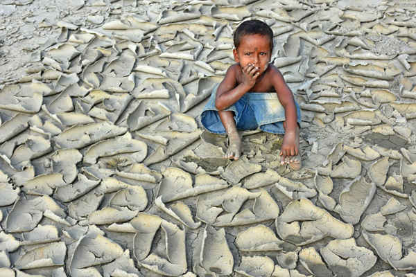 Bức ảnh “Dryness” của Chinmon Biswas, Ấn Độ, người chiến thắng giải thưởng về biến đổi khí hậu. Trong bức ảnh, một đứa trẻ ngồi trên mảnh đất nứt nẻ và từng mảng đất bị bóc ra do hạn hán