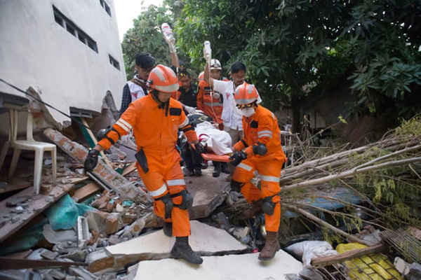 Nhân viên cứu hộ giải cứu người sống sót trong trận động đất, có tên Ida, một nhà cung cấp thực phẩm, từ đống đổ nát của một nhà hàng bị sụp đổ. Ảnh: Bay Ismoyo / AFP / Getty Images
