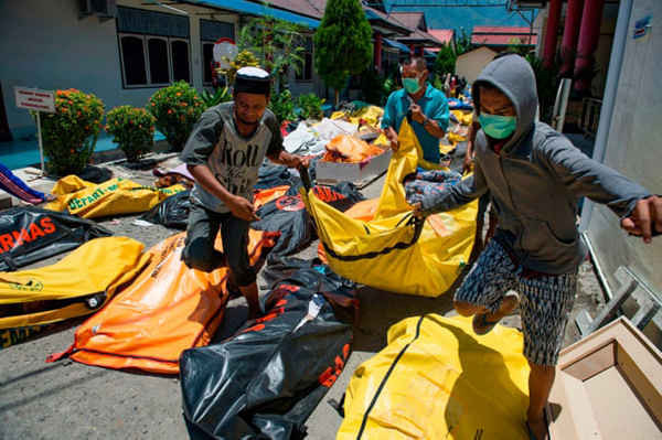 Các thành viên trong gia đình chuyển thi thể người thân của họ đến khu tổ hợp của một bệnh viện cảnh sát ở Palu. Ảnh: Bay Ismoyo / AFP / Getty Images