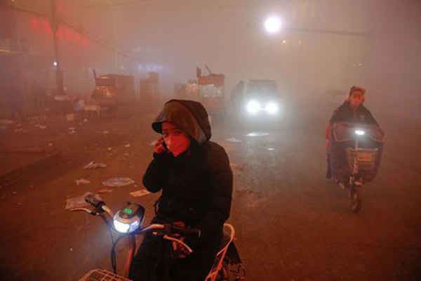 Mọi người đi đường trong bầu không khí ô nhiễm nặng đến mức cảnh báo đỏ được phát hành tại Shengfang, tỉnh Hà Bắc, Trung Quốc vào ngày 19/12/2016. Ảnh: Damir Sagolj