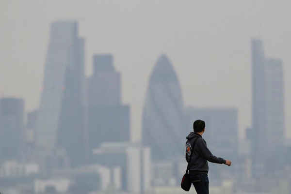 Một người đàn ông đi qua Greenwich Park khi một đám mây ô nhiễm nằm trên đường chân trời London vào ngày 3/4/2014. Ảnh: Reuters / Luke MacGregor