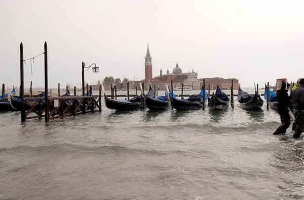 Mọi người đi bộ trên lối đi ở Quảng trường Saint Mark bị ngập vào thời điểm nước cao theo mùa ở Venice, Italy ngày 29/10/2018. Ảnh: Reuters / Manuel Silvestri