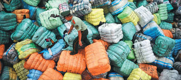 Một người bảo vệ biên giới ở Thâm Quyến, tỉnh Quảng Đông, Trung Quốc kiểm tra hàng loạt bọc chất thải hàng dệt may nhập lậu vào Trung Quốc. Ảnh: Tân Hoa Xã