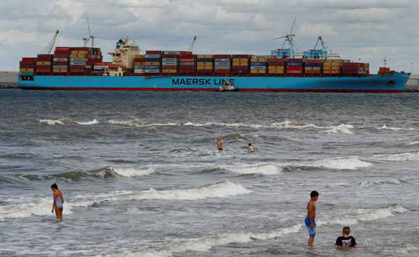  Trẻ em chơi trên biển tại New Brighton khi con tàu container Maersk Line được hỗ trợ bởi tàu kéo khi nó di chuyển trên sông Mersey ở Liverpool, Anh vào ngày 31/7/2018. Ảnh: Phil Noble