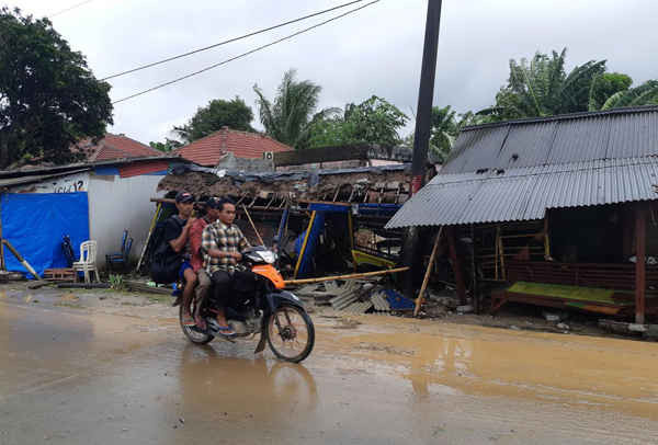 Người dân đi xe máy qua các cửa hàng nhỏ bị đổ sập sau khi sóng thần tấn công bãi biển Carita ở Pandeglang, tỉnh Banten, Indonesia vào ngày 23/12/2018. Ảnh: Adi Kurniawan