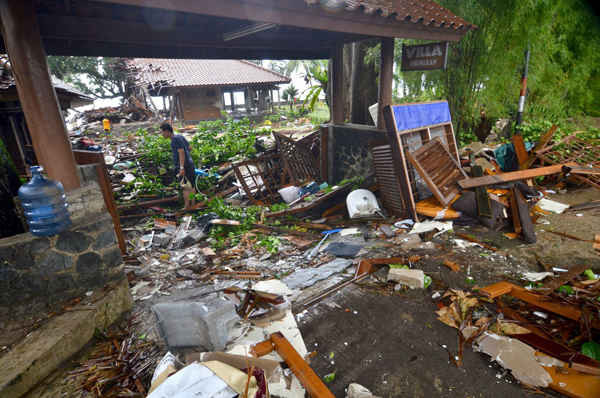 Một người đàn ông đi giữa những mảnh vỡ từ các tòa nhà bị hư hỏng ở Carita, Indonesia. Ảnh: RONALD / AFP / AFP / Getty Images