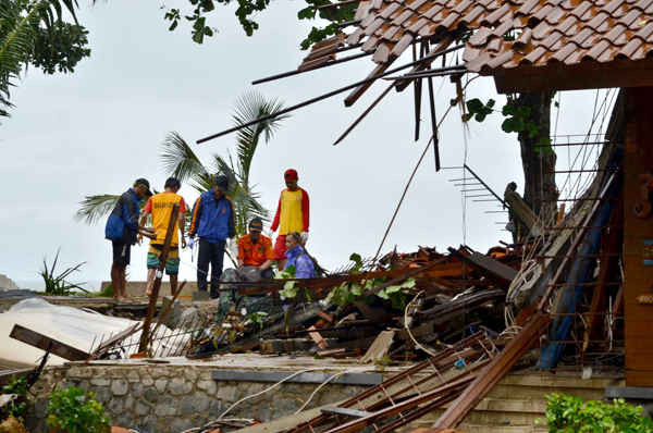 Các quan chức nhìn qua đống đổ nát của các tòa nhà bị hư hại ở Carita, Indonesia. Ảnh: RONALD / AFP / AFP / Getty Images
