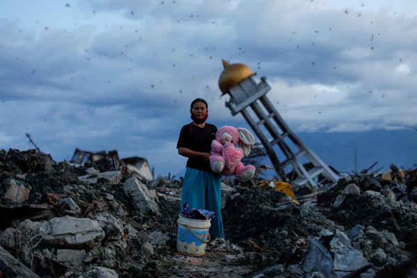 Người phụ nữ cầm một món đồ chơi thỏ nhồi bông sau khi cô tìm thấy nó từ ngôi nhà bị phá hủy của cô, nơi cô cho biết đã mất ba đứa con của mình, ở Palu, Central Sulawesi, Indonesia vào ngày 7/10/2018. Ảnh: REUTERS / Jorge Silva