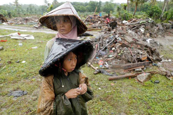 Hình ảnh một phụ nữ và trẻ em bên cạnh các mảnh vỡ sau thảm họa sóng thần ở Sumur, tỉnh Banten, Indonesia vào ngày 26/12/2018. Ảnh: REUTERS / Jorge Silva