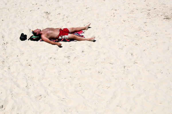 Một người đàn ông nằm trên bãi biển Glenelg trong thời tiết nắng nóng ở thành phố Adelaide, Nam Úc vào ngày 26/12/2018. ẢNH: EPA / EFE