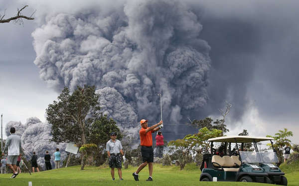Mọi người chơi golf khi một đám tro bụi bốc lên từ núi lửa Kilauea trên Đảo Lớn của Hawaii vào ngày 15/5. Ảnh: Mario Tama / Getty Images