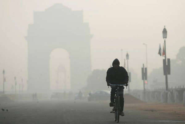 Một người đàn ông đạp xe trước Cổng Ấn Độ bị che khuất trong sương khói ở New Delhi, Ấn Độ vào ngày 26/12/2018. Ảnh: Reuters/Adnan Abidi