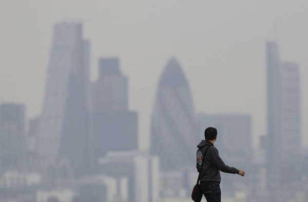 Một người đàn ông đi qua Công viên Greenwich khi khói bụi bao trùm bầu trời London vào ngày 3/4/2014. Ảnh: Reuters / Luke MacGregor