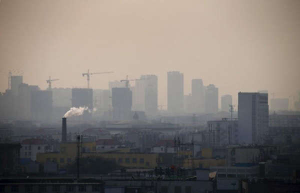 Khói bốc lên từ một ống khói giữa các ngôi nhà khi các tòa nhà cao tầng đang được xây dựng vào một ngày bụi mù ở trung tâm thành phố Đường Sơn, tỉnh Hà Bắc vào ngày 18/2/2014. Ảnh: Reuters / Petar Kujundzic