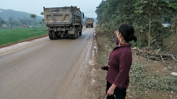Bà Nguyễn Thị Hường, ở thôn Đồng Khang bức xúc chỉ tay về đoàn xe vận chuyển đất gây ô nhiễm